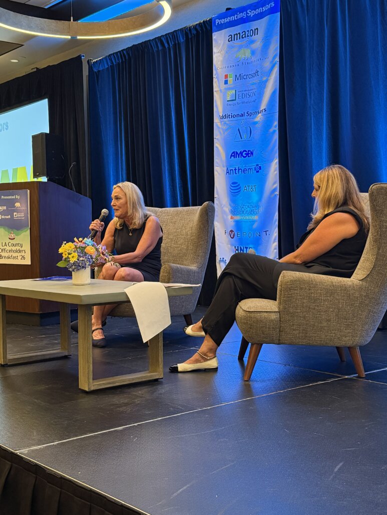 California Strategies Partner Lisa Gritzner, holding a microphone, moderates a fireside chat with Los Angeles County Supervisor Kathryn Barger on stage at VICA's 2026 LA County Officeholders Breakfast